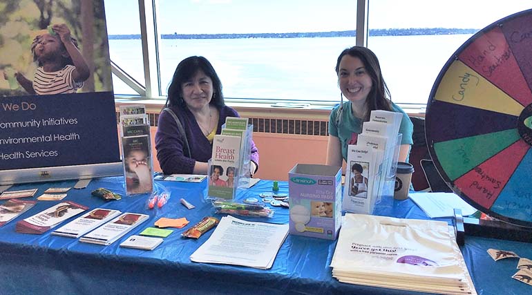 Two smiling people sitting at table with brochures and supplies.
